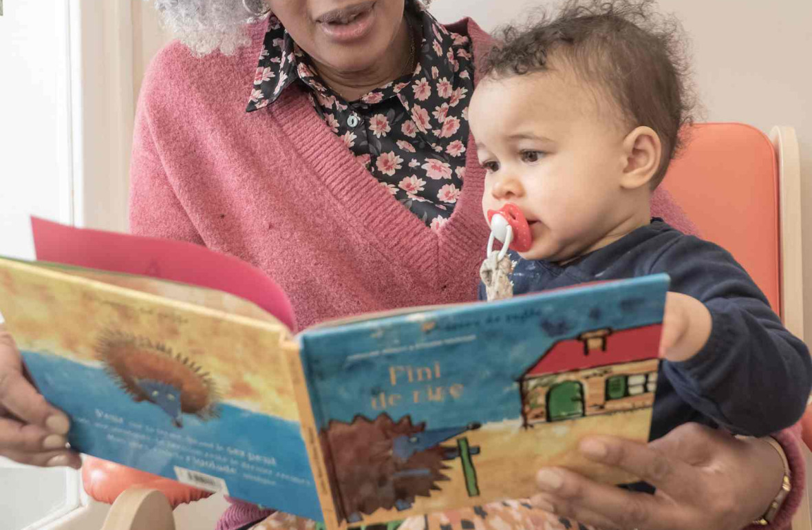 Une pro en crèche qui lit un livre à un enfant