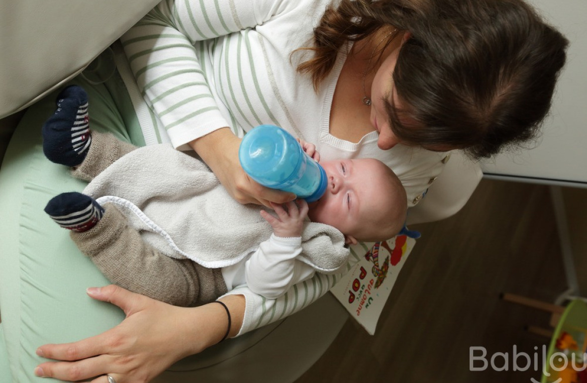 Une pro en crèche donnant le biberon à un bébé