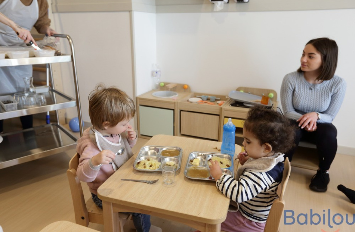 Une pro crèche en crèche et deux enfants qui mangent 