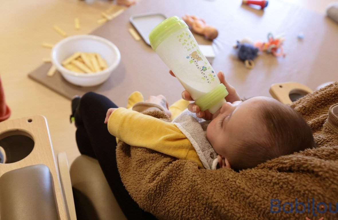 Une pro en crèche qui donne le biberon à un bébé 