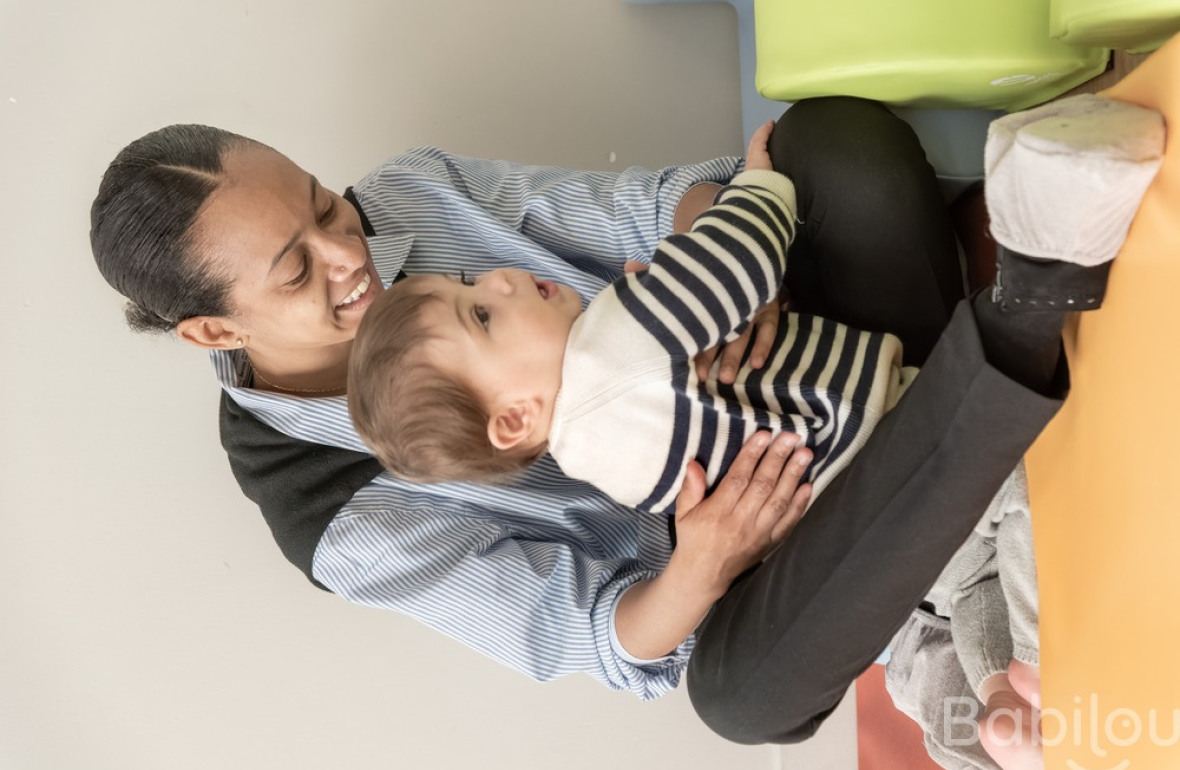 Une pro en crèche assise avec un enfant