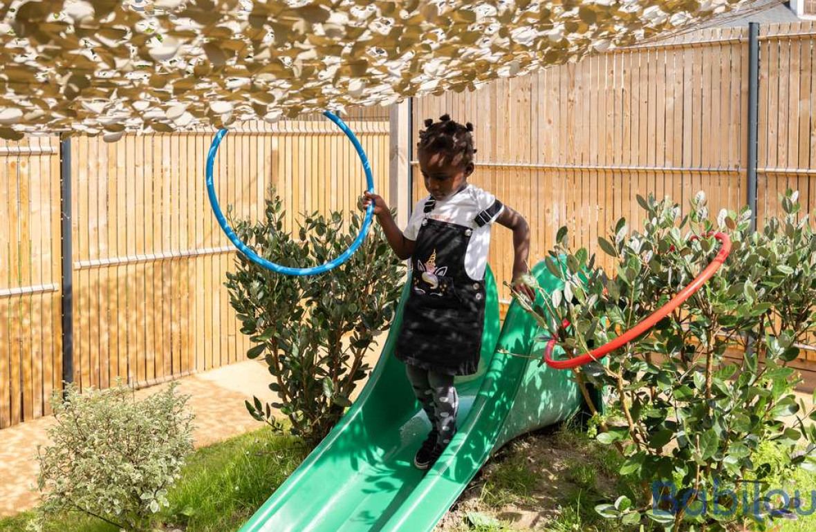 Une petite fille en crèche qui joue dans le jardin