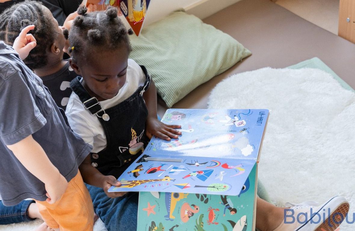 Une petite fille en crèche qui regarde un livre