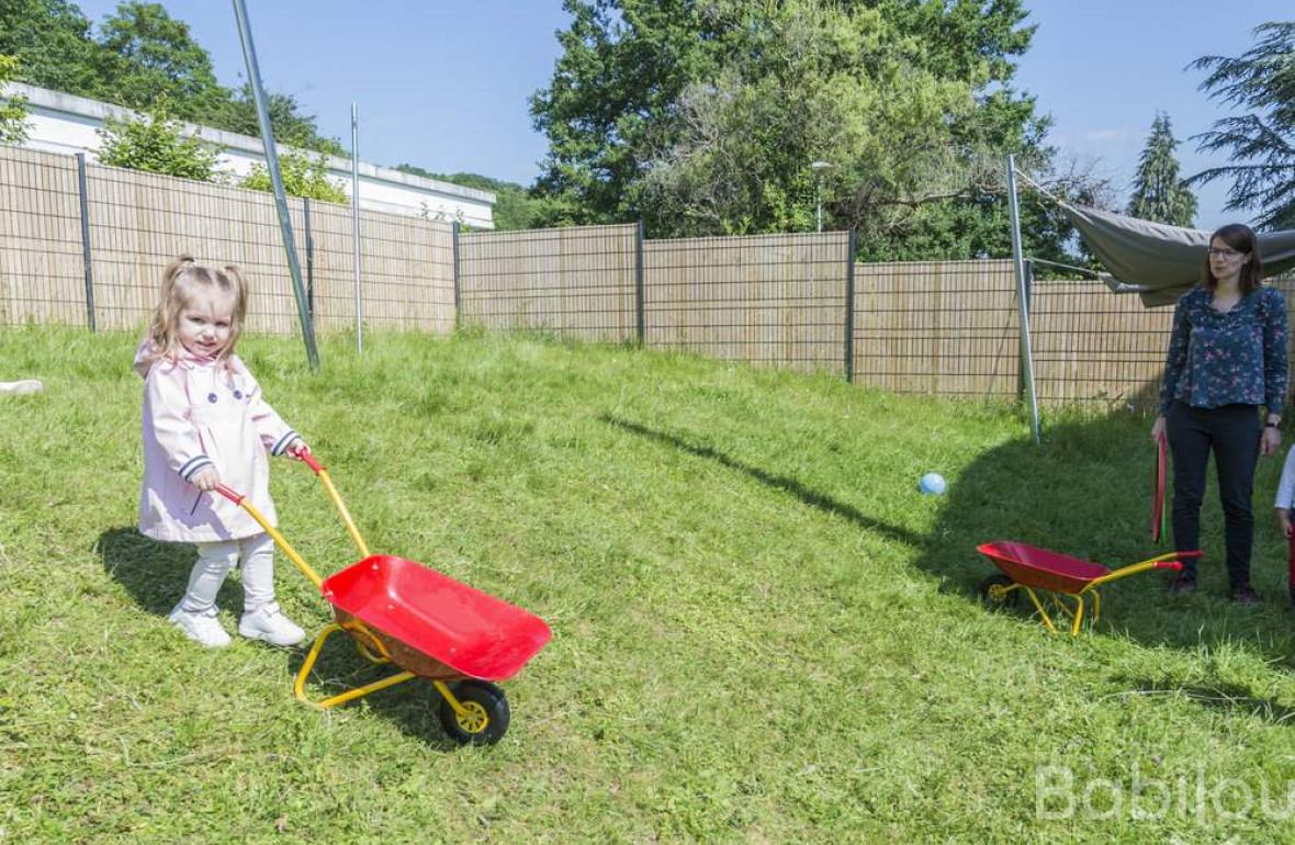 Une pro en crèche qui joue avec une enfant dans le jardin