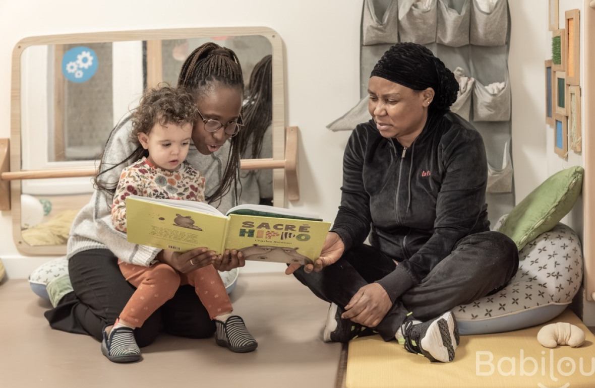 Deux pro en crèche avec un enfant lisant un livre