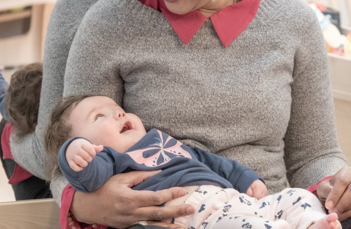 Une professionnelle en crèche assise avec un bébé