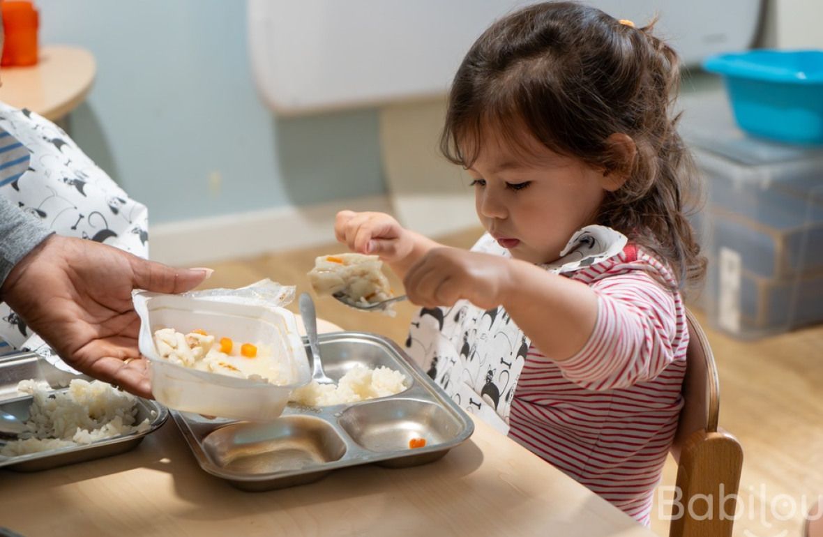 Une enfant en crèche qui mange