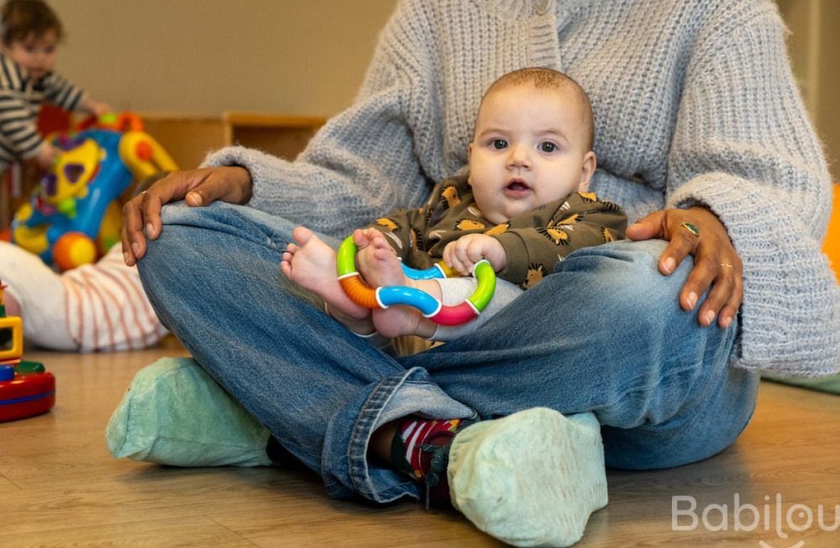 Une pro en crèche assise avec un bébé