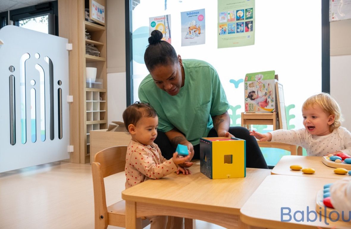 Une pro en crèche en interaction avec deux enfants 