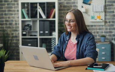 Un femme en train de travailler, souriante devant son ordinateur