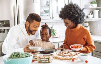 Deux parents et un enfant, qui cuisinent à la maison