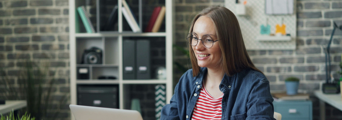 Un femme en train de travailler, souriante devant son ordinateur