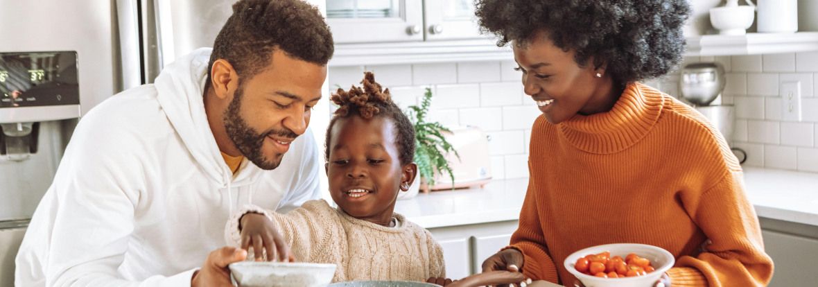 Deux parents et un enfant, qui cuisinent à la maison