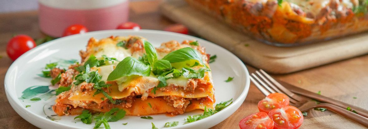 Un plat de lasagne à côté d'une assiette avec une part de lasagne