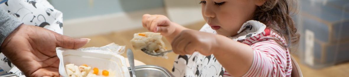 Une enfant en crèche qui mange